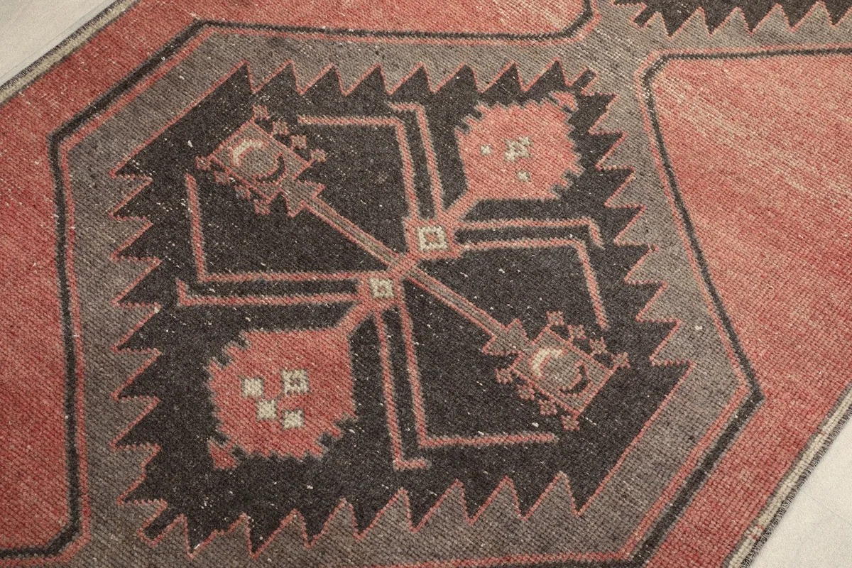 Intricate close-up of a charcoal and rust geometric motif within the rug, highlighting weaving details.