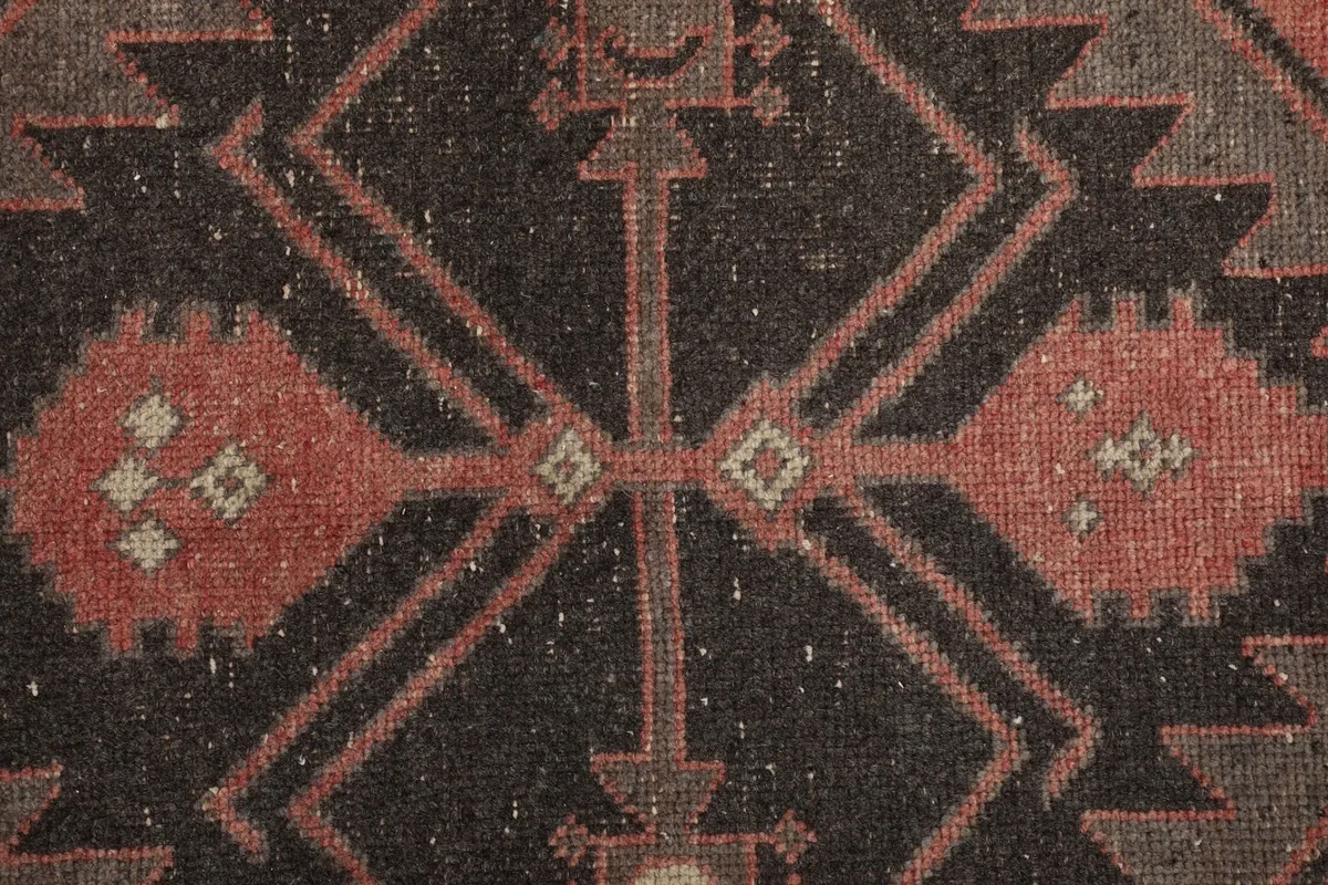 Extreme close-up of the rug's central geometric design, showing wool texture and minor wear.