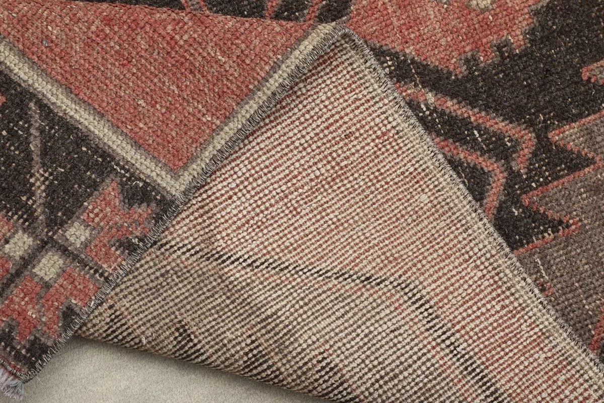 Folded corner of the rug revealing the tightly woven cotton foundation on the reverse side.