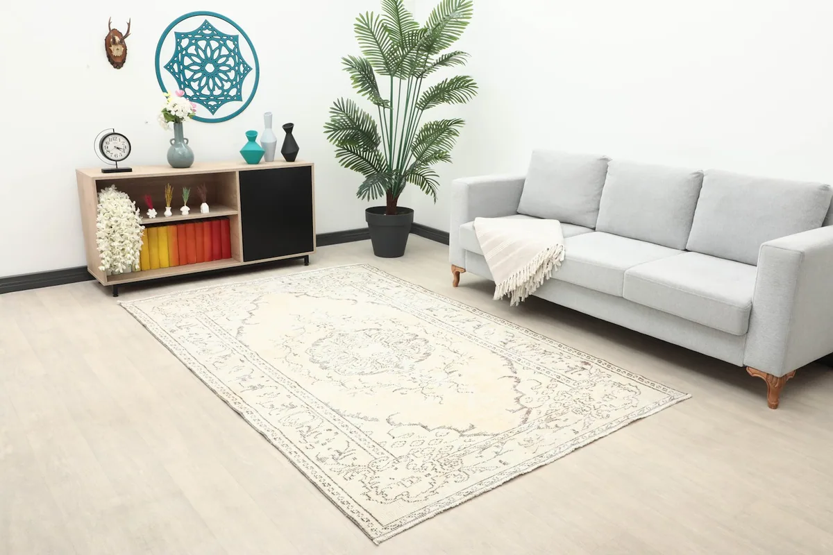 Vintage Anatolian rug displayed in a living room setting with a gray sofa and wooden console