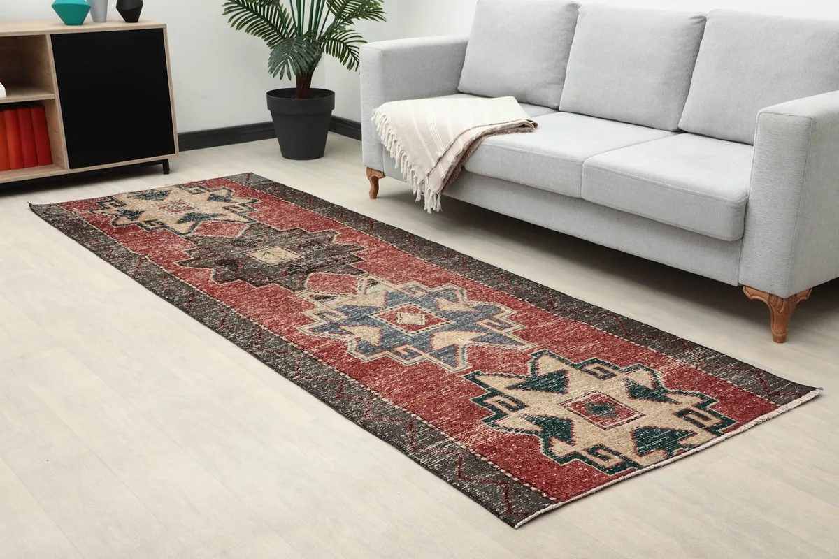 Vintage Anatolian runner rug displayed in a living room setting next to a gray sofa.