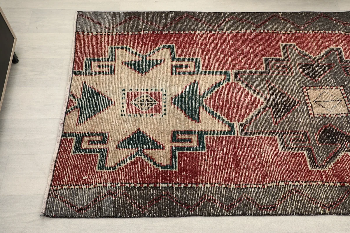 Detailed view of the rug's tribal motifs and the distressed texture of the wool pile.