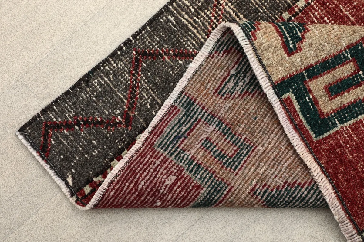 Corner of the rug folded to show the thickness and the back of the hand-knotted cotton foundation.
