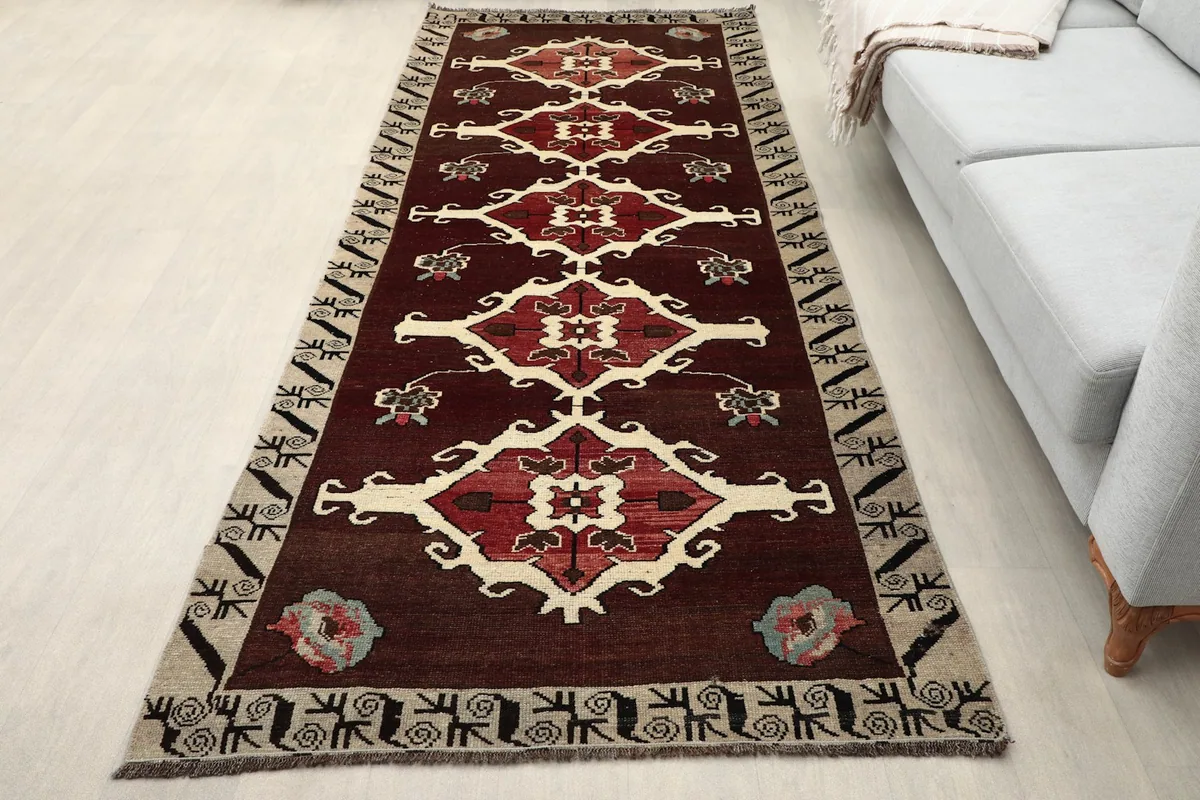 Vintage red runner rug in a room setting, showing its length next to a sofa