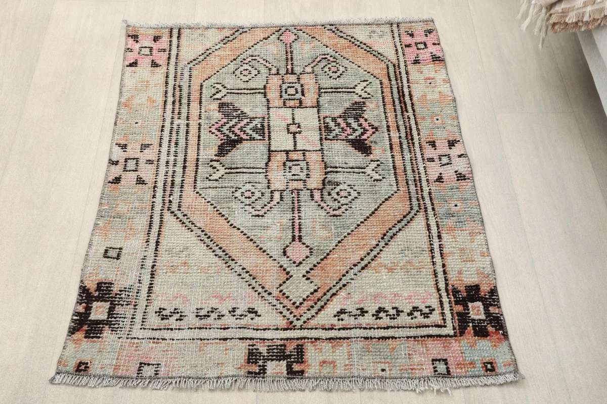 Vintage Anatolian rug with geometric pattern in gray and rose, viewed from above.