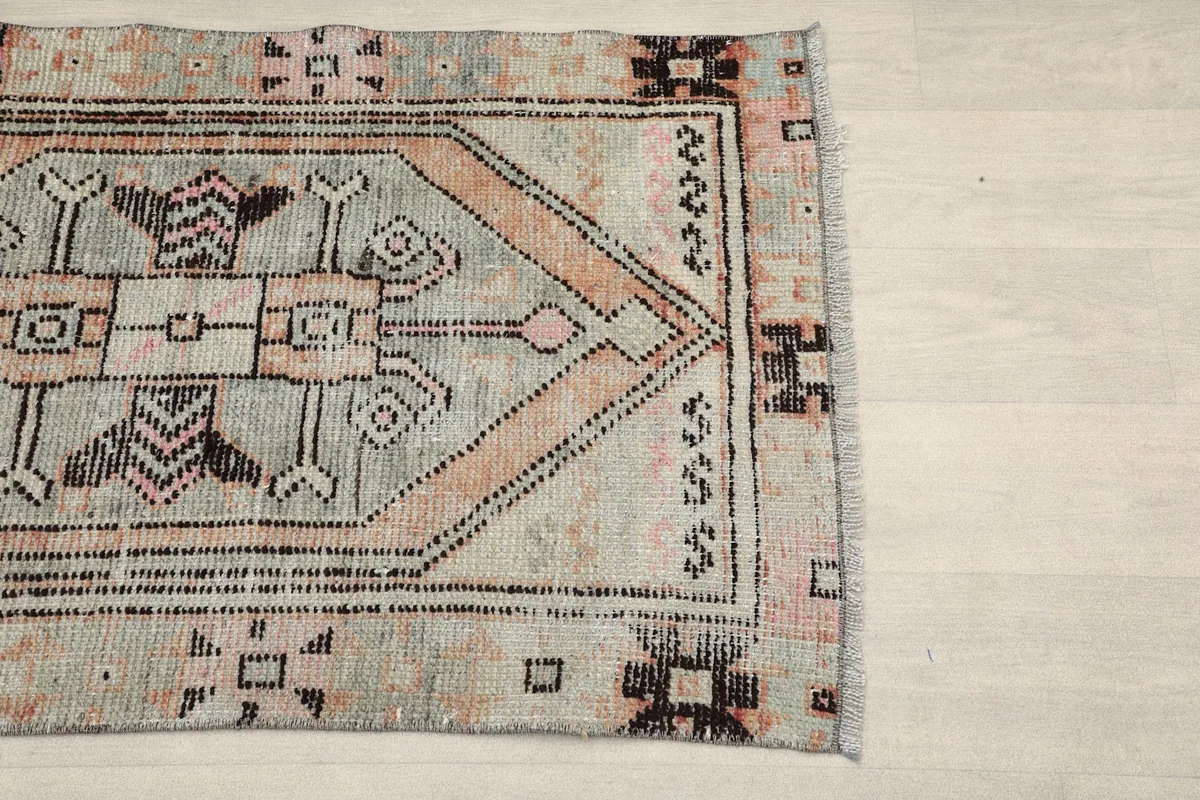 Close-up of the geometric motifs and border on the right side of the gray and rose rug.