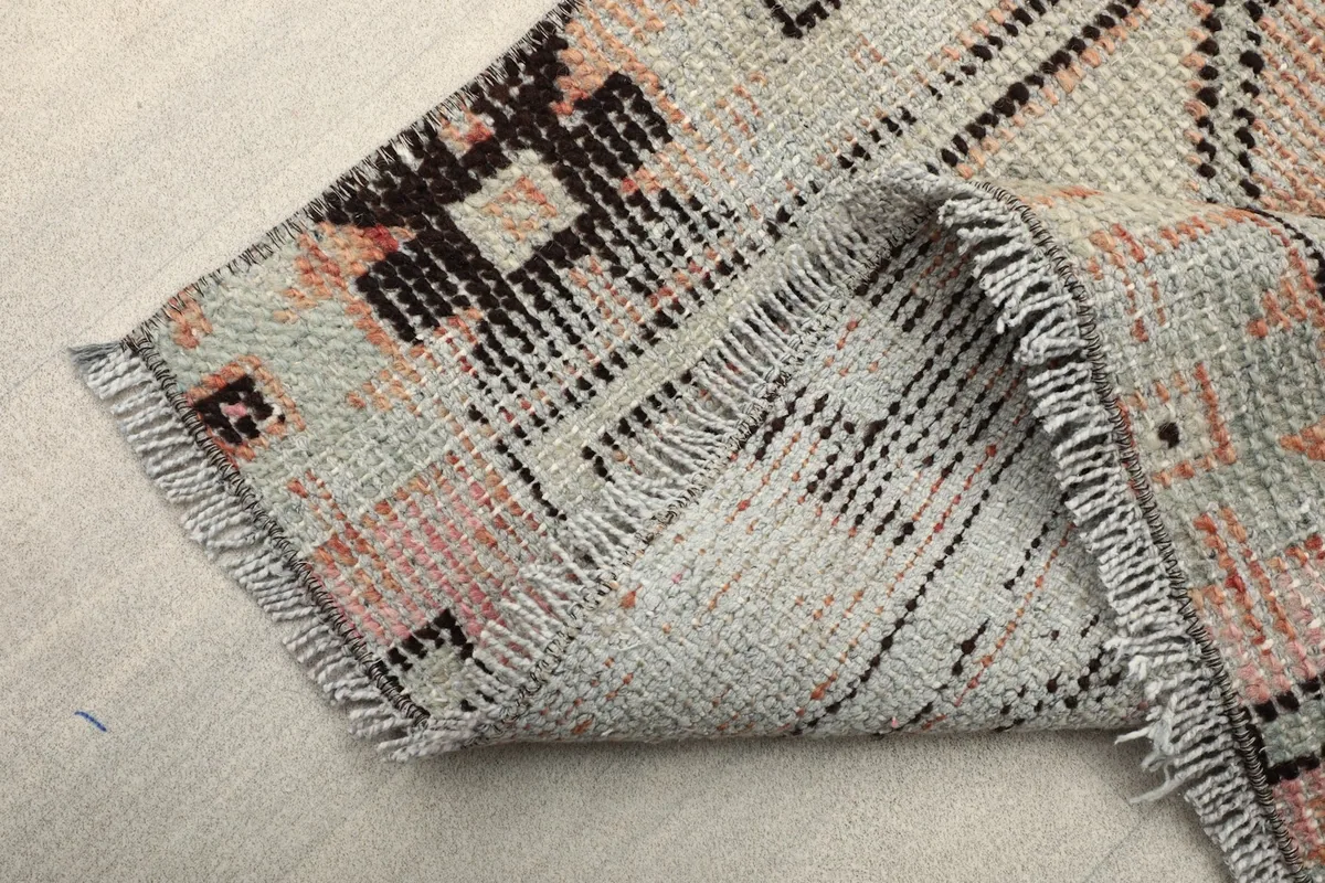 View of the short, natural cotton fringe and the hand-knotted construction at the edge of the rug.