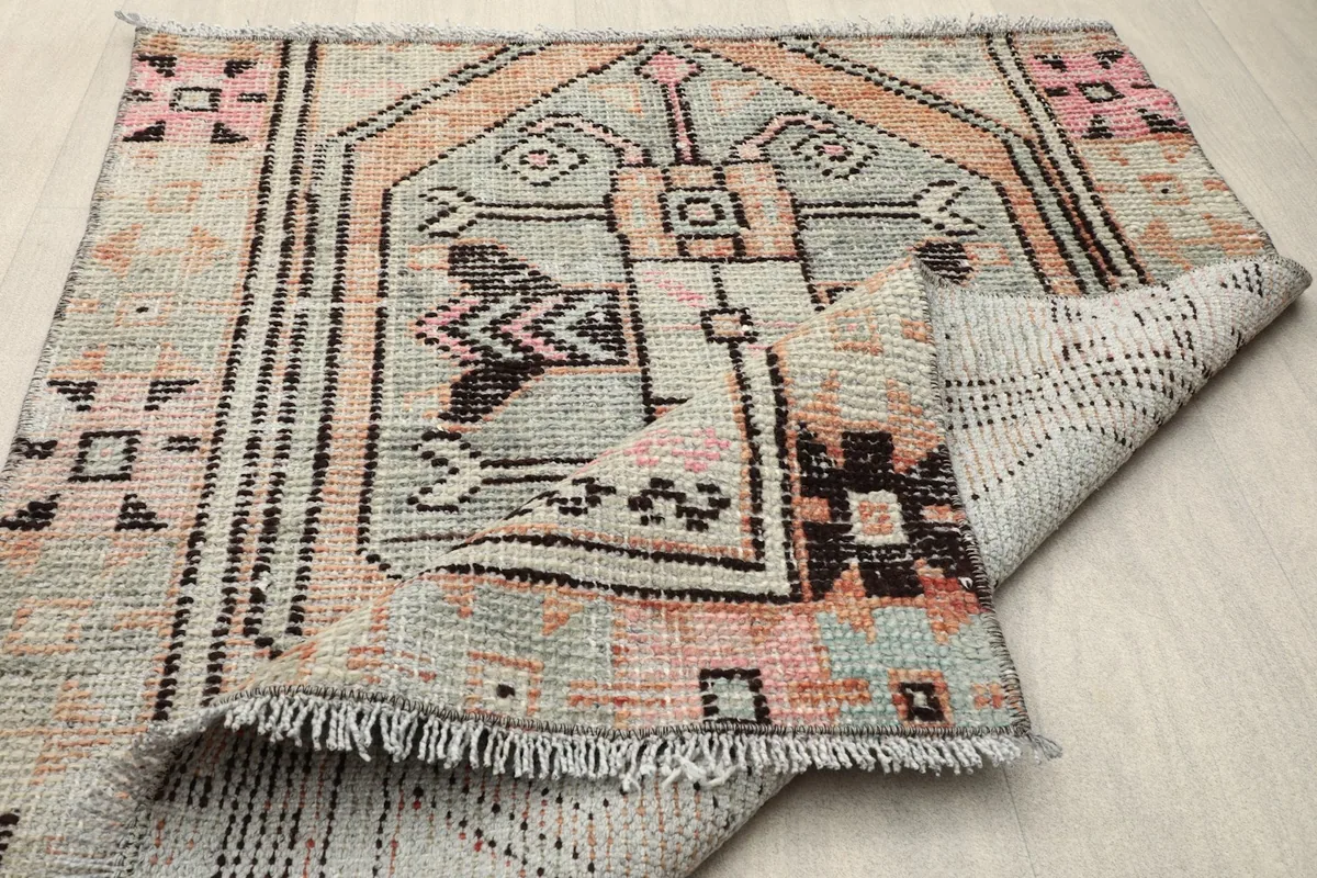 Rug folded to display its flexibility, fringe, and the hand-knotted details of the wool pile.