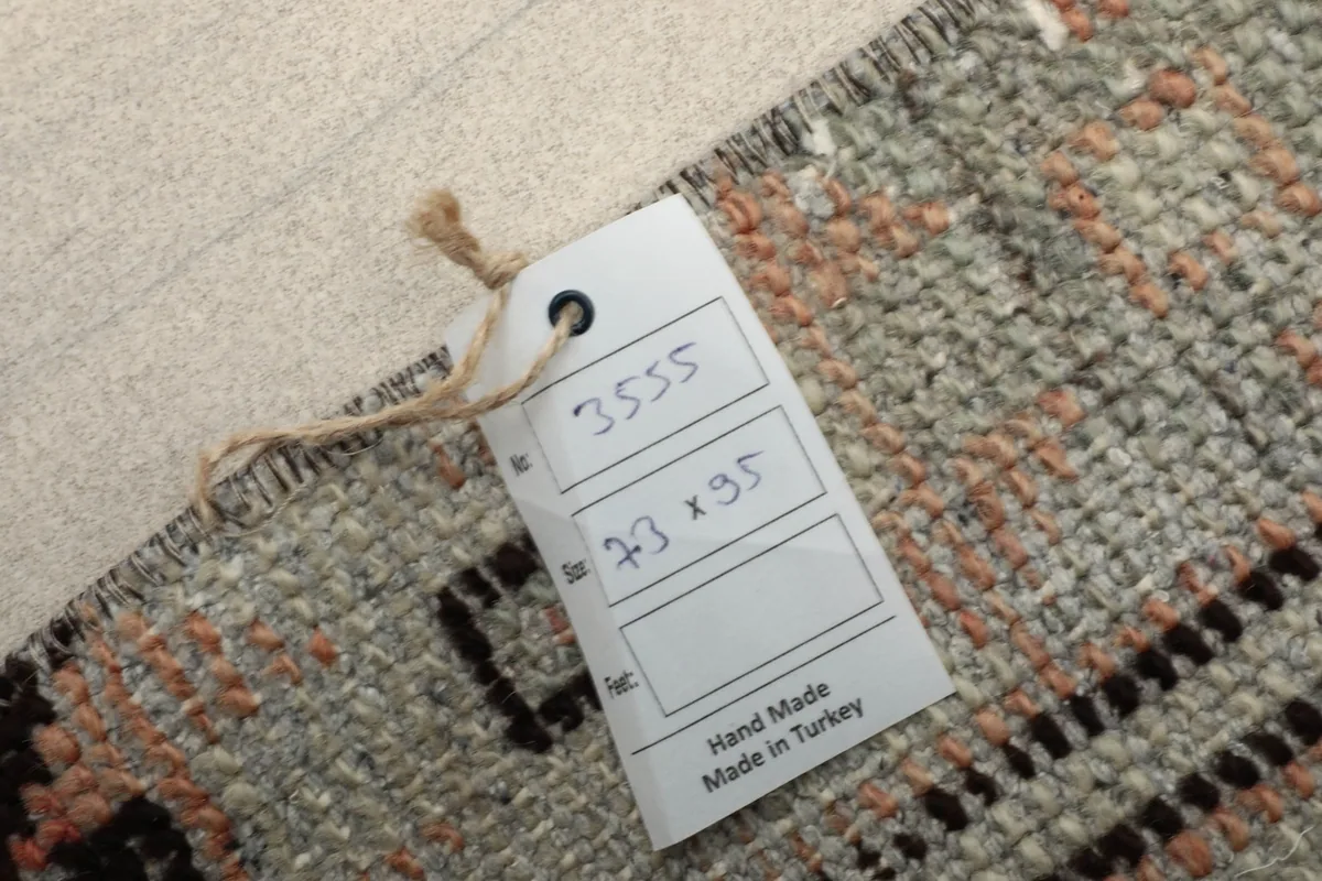 Close-up of the rug's corner with a tag indicating 'Hand Made in Turkey' and dimensions.