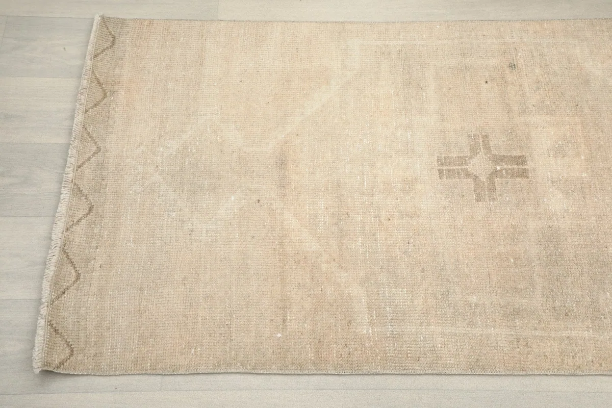 Detail angle of the rug's surface, showing the edge finish and a faded tribal pattern