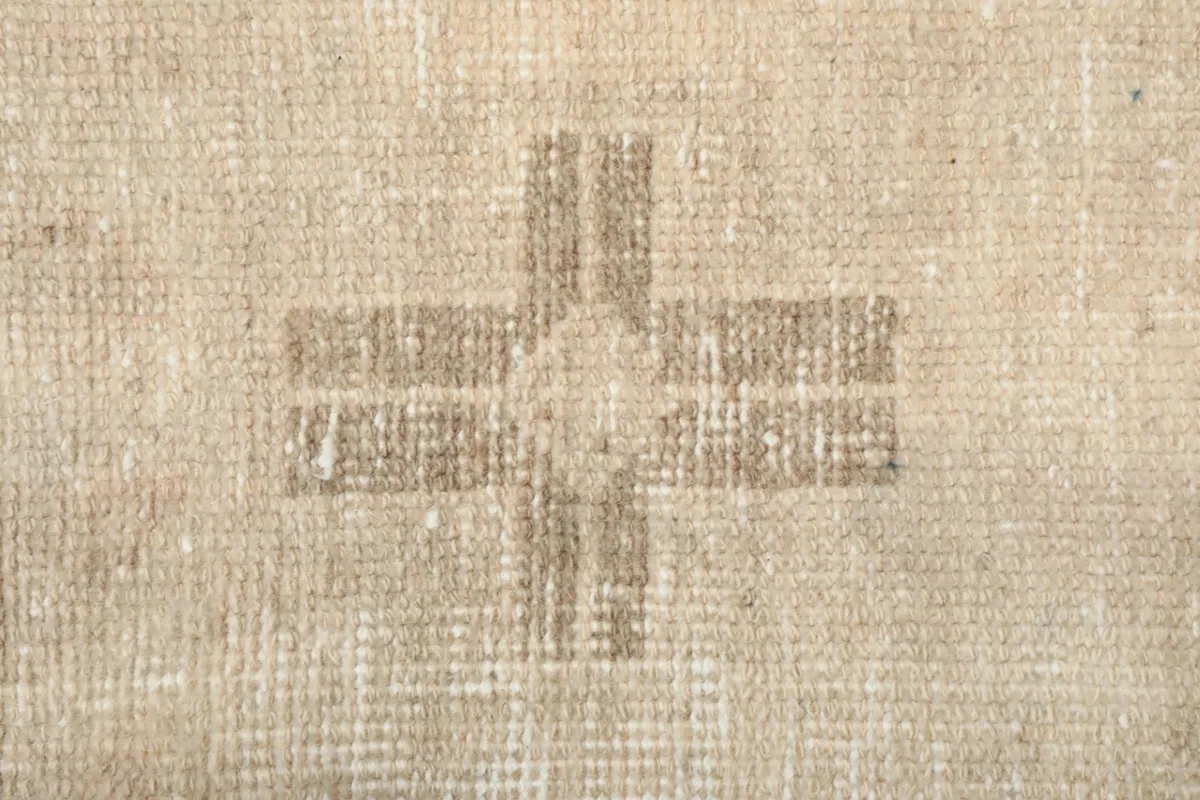 Close-up of a smaller tan cross-like tribal motif with visible texture and patina
