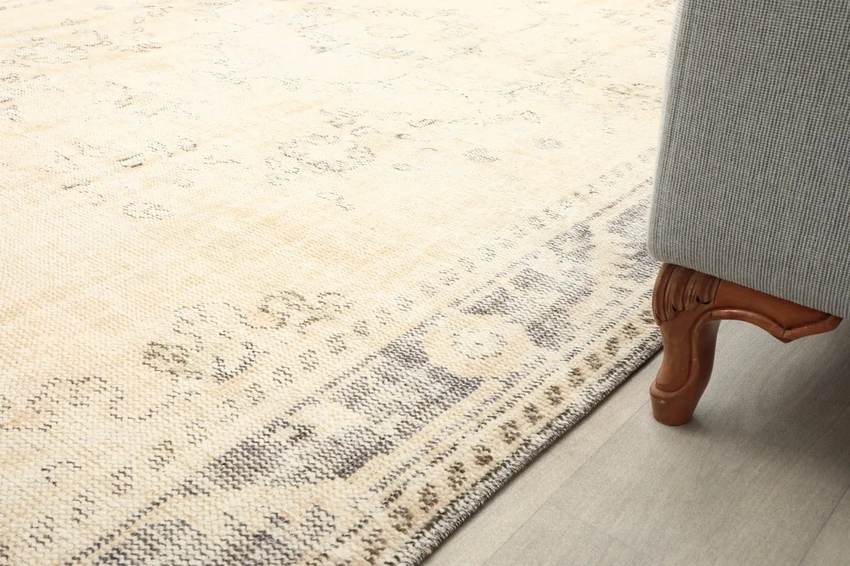 Close-up of the rug's border and field, with a sofa leg in the corner, showing scale