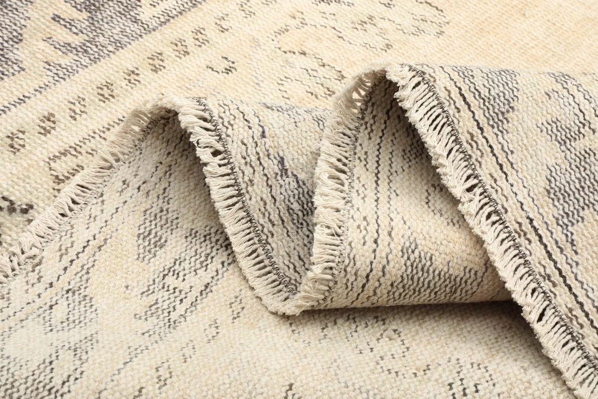 Side view of the rug folded, revealing the low pile and the texture of the wool