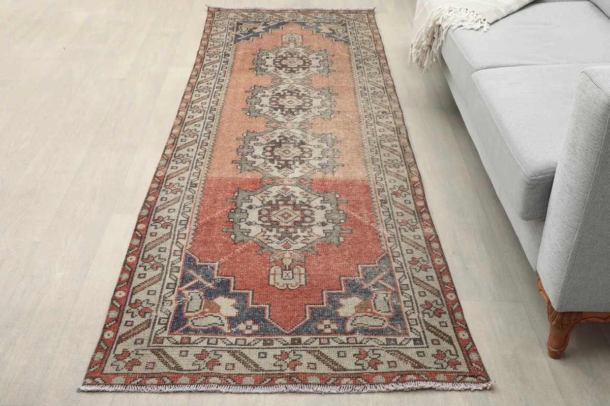 Rust runner rug in a modern living room setting next to a light gray sofa and light wood floor.