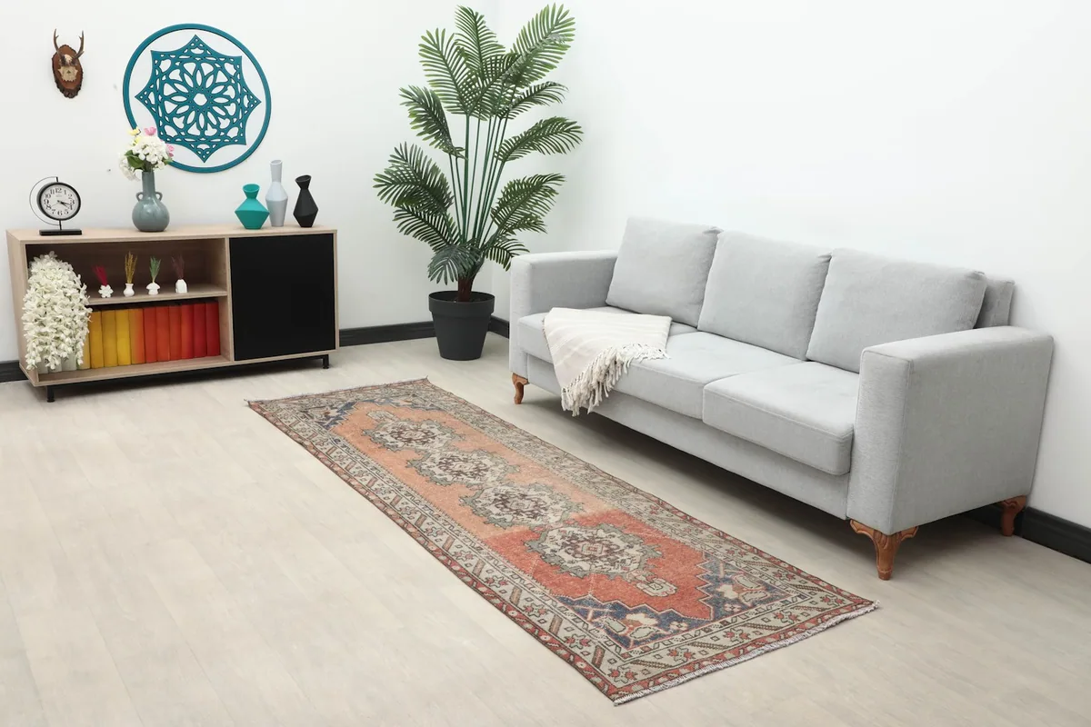 Long view of the vintage Anatolian runner rug in a room with a sofa, plant, and decorative shelf.