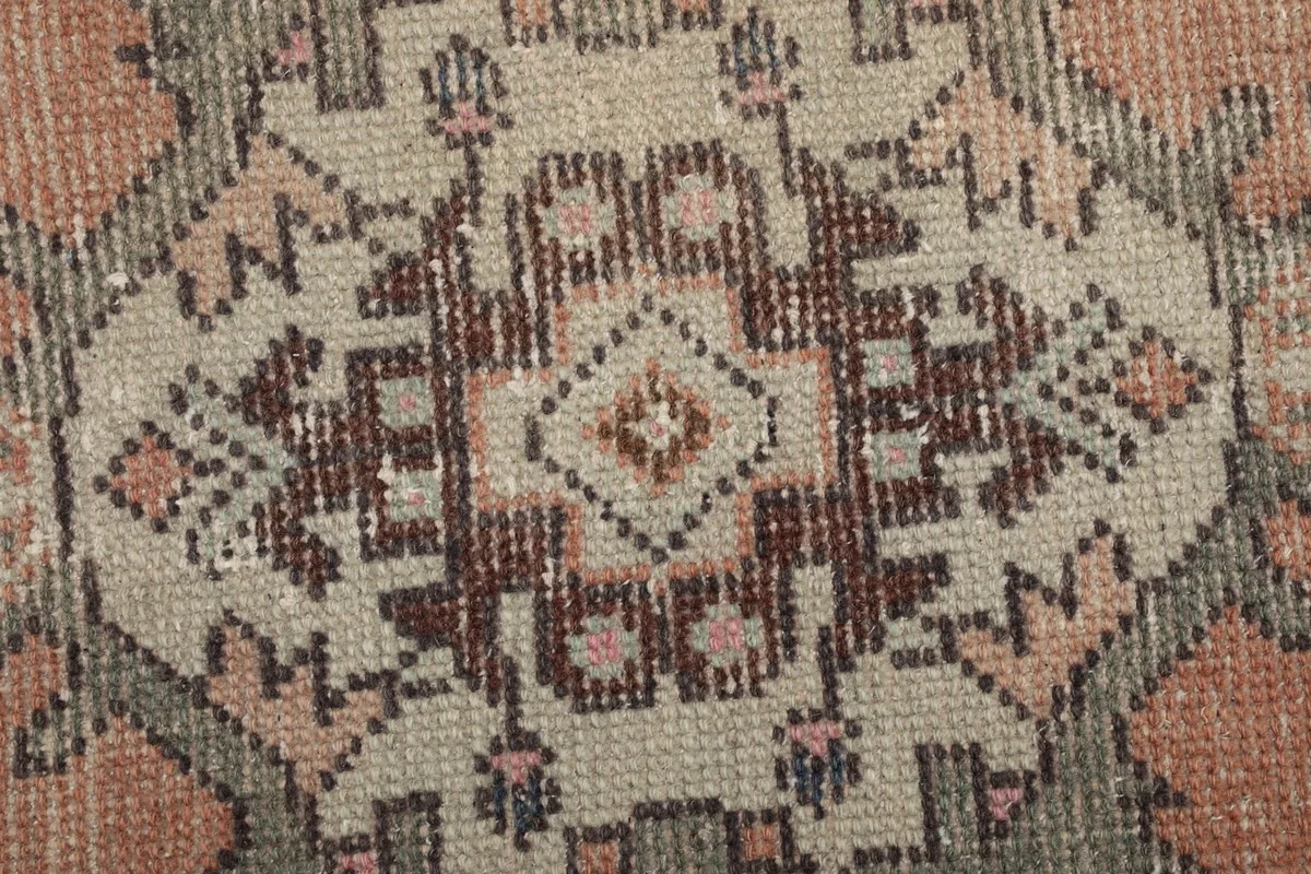 Extreme close-up of a central geometric medallion showing wool texture and color variations.