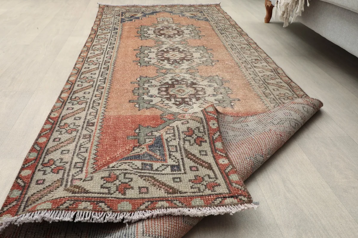 Runner rug partially rolled, showcasing the low pile and the softness of the vintage wool.