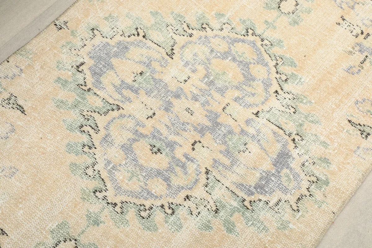 Detailed view of the central blue and green medallion motif on the cream field.