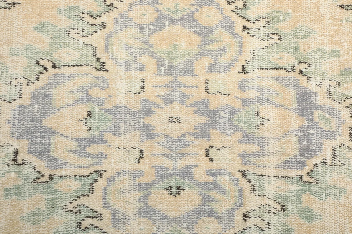 Close-up of the rug's surface, showing the faded colors and texture of the wool pile.