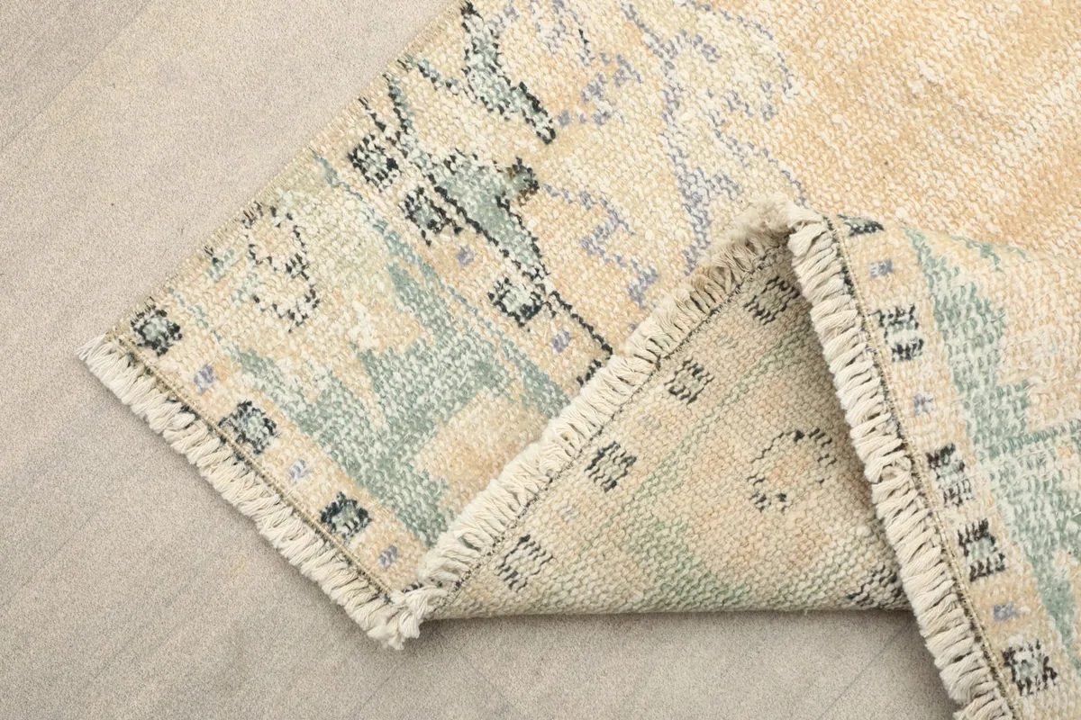 Corner of the runner rug folded back, revealing the hand-knotted construction and cotton foundation.