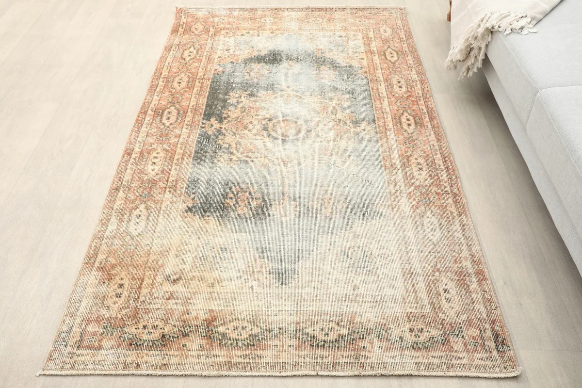 Overhead view of the vintage gray and rust area rug in a living space next to a sofa.