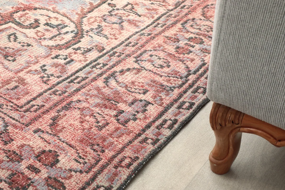 Rug placed under a chair, showing a portion of its pattern and border