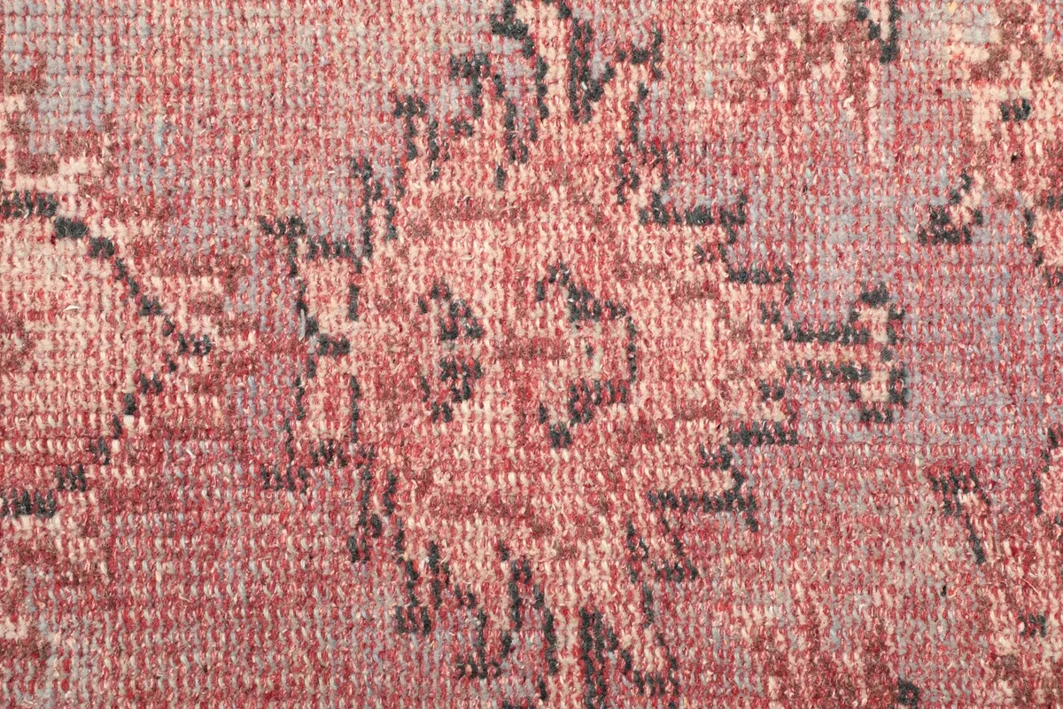 Close-up of the low wool pile texture and faded rose and blue patterns