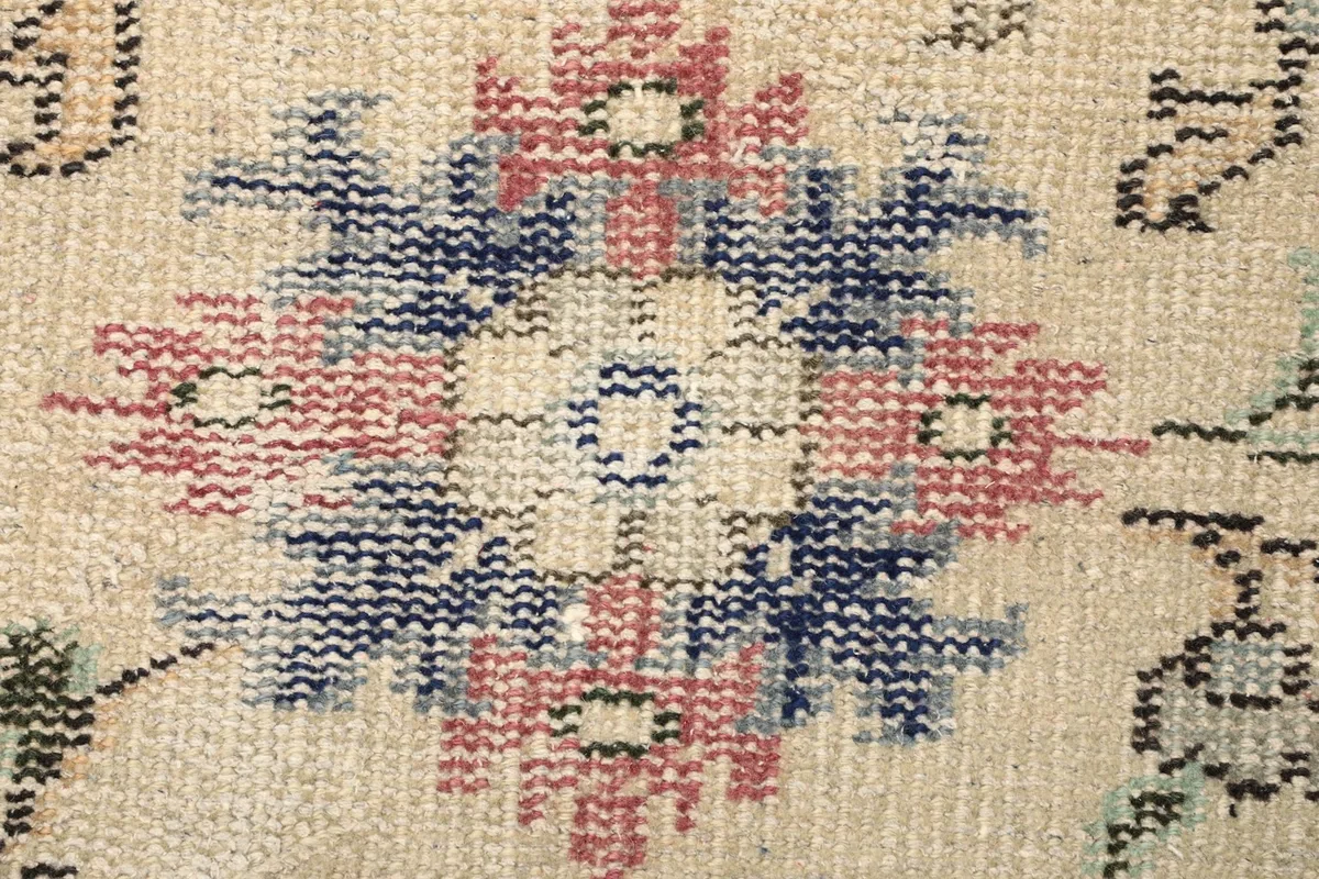 Macro view of a central floral motif with rose and blue tones and visible knotting