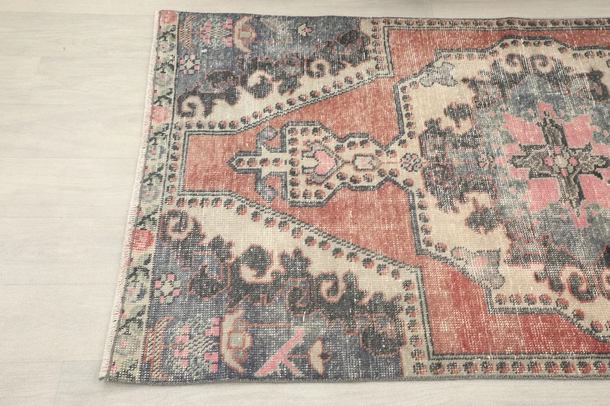 Detail of the vintage rug's corner, highlighting the geometric motifs and muted colors