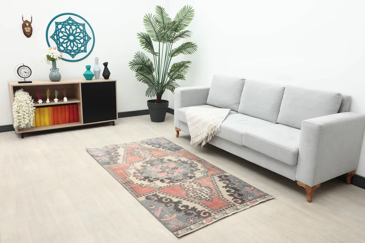 Small vintage rug placed in a living room setup with a gray sofa and light wood floor