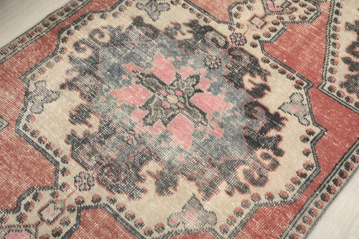 Close-up of the central medallion design, featuring pink, gray, and beige details