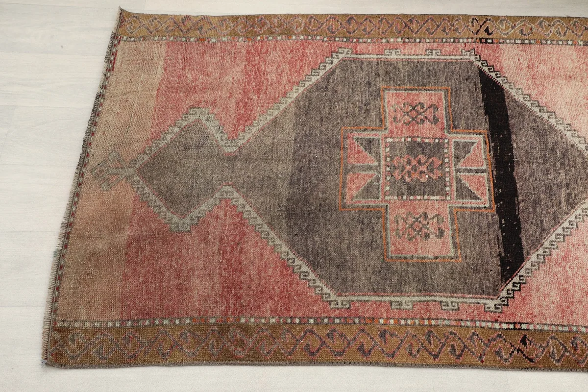 Angled shot highlighting the rose field and the central charcoal geometric medallion of the rug