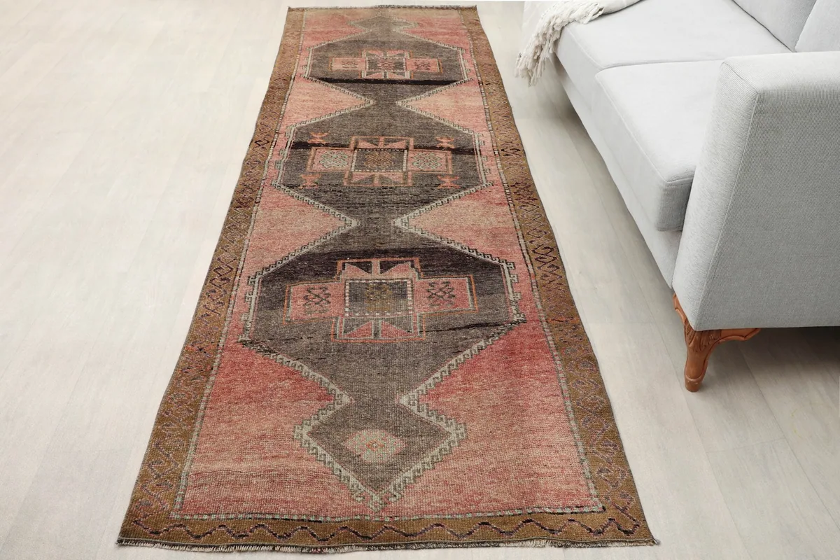 Rose and charcoal runner rug placed in a room, showing its length next to a light gray sofa
