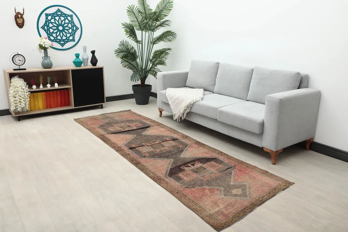 Wide shot of the rose and charcoal runner rug in a living space with a sofa and decor