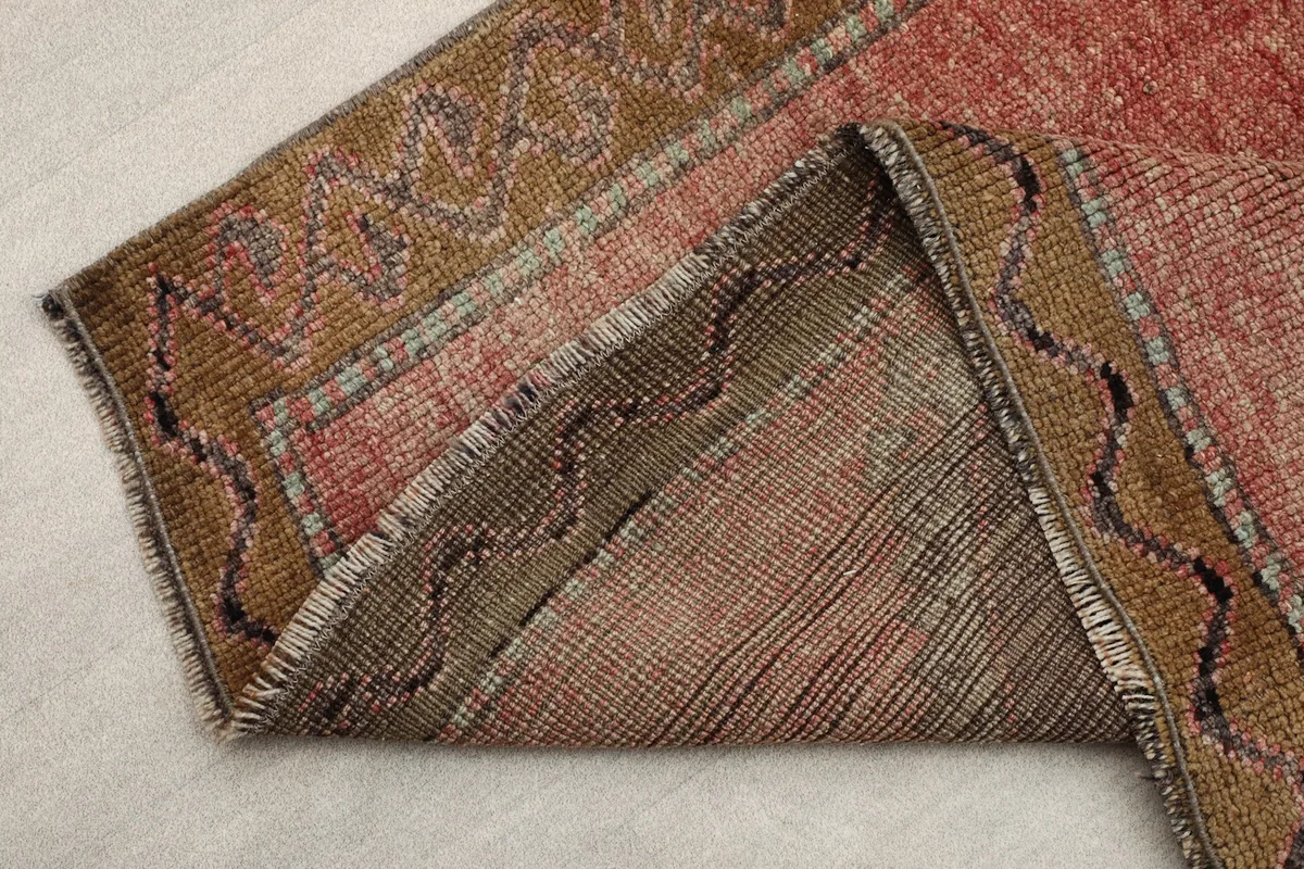 Folded corner of the rug showing the reverse side and the construction of the wool pile and cotton foundation