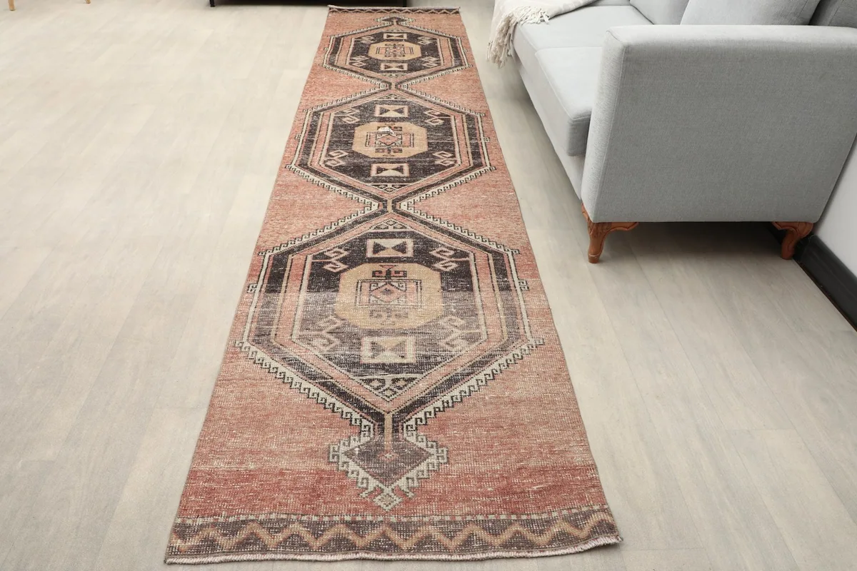 Rust geometric runner rug laid out in a living room next to a gray sofa.
