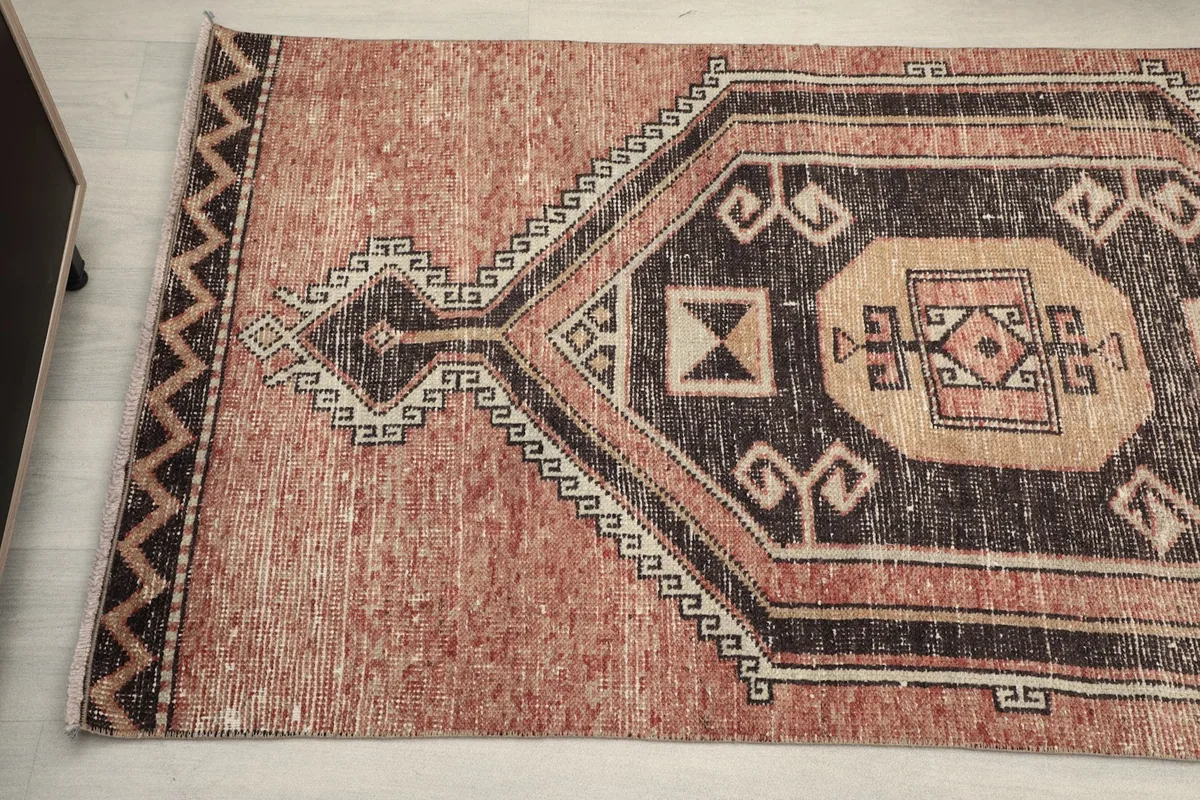 Close-up of the other end of the rust runner rug, showing border patterns and colors.