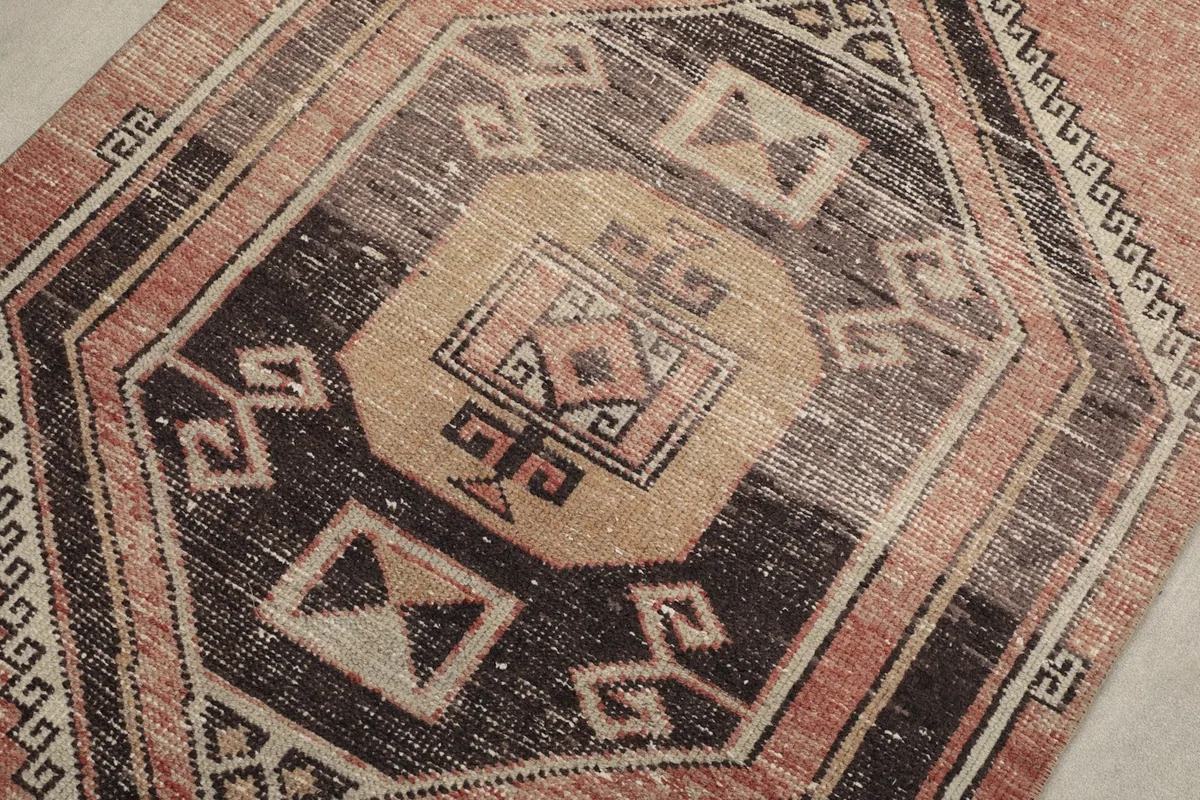 Detailed view of a central geometric medallion in black, tan, and rust tones.