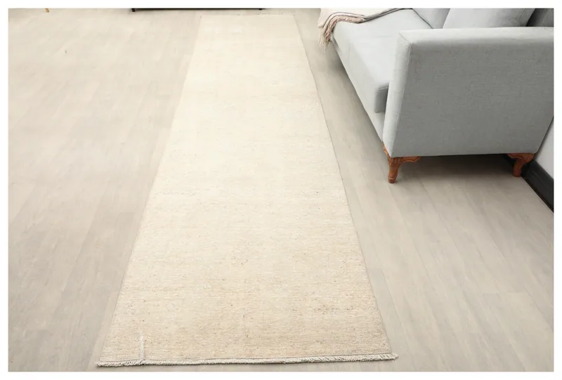 Full overhead view of the beige and ivory vintage runner on a light floor.