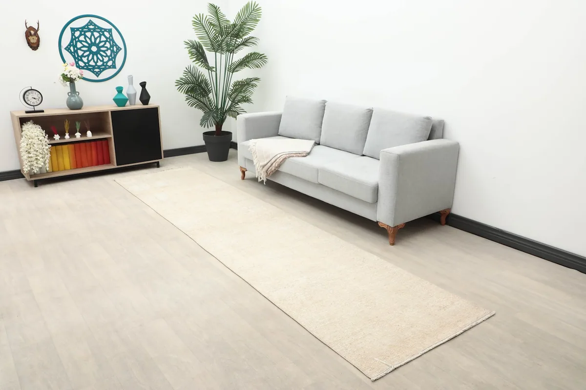 Long view of the beige runner in a living space with a gray sofa and decor.