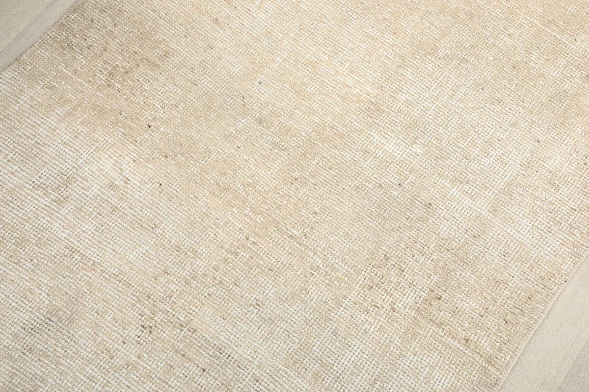 Detailed close-up of the beige wool pile, showing the hand-knotted texture and tonal variations.