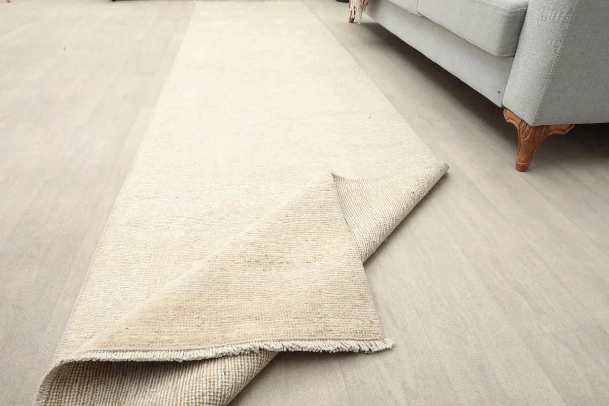 The beige runner partially folded on the floor, indicating its flexibility.