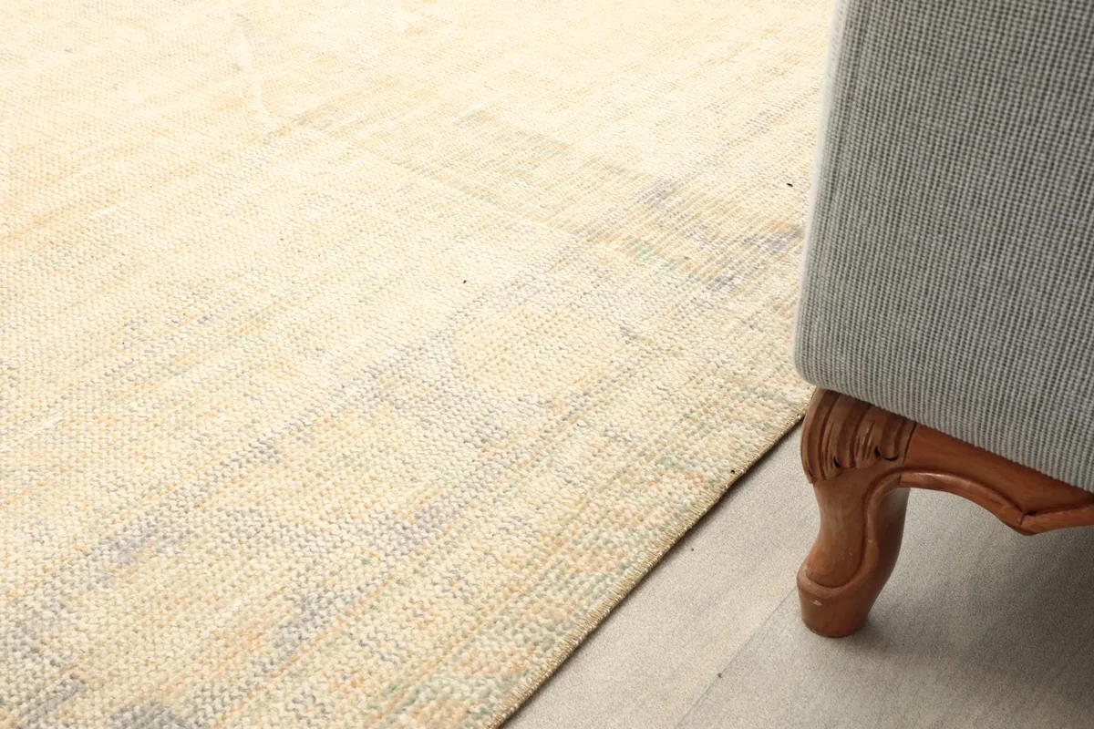 Close-up of the rug next to a sofa leg, showing the subtle patterns and low pile