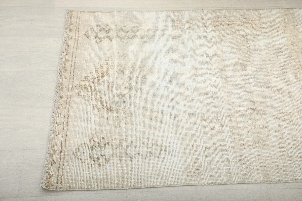 Detailed view of the rug's patterns and edge, showing the hand-knotted texture and vintage wear.