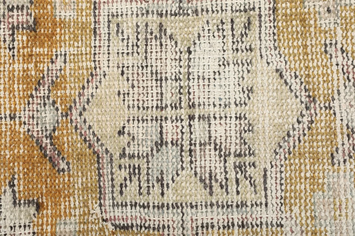 Detailed view of the wool pile texture and faded geometric pattern within the rug's central design.