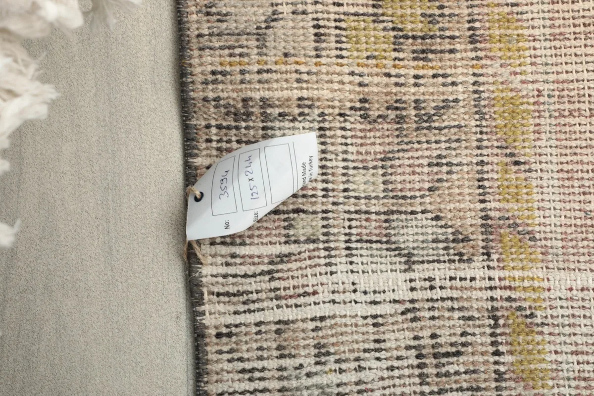 Close-up of the rug's back, detailing the weave and a tag indicating its dimensions.