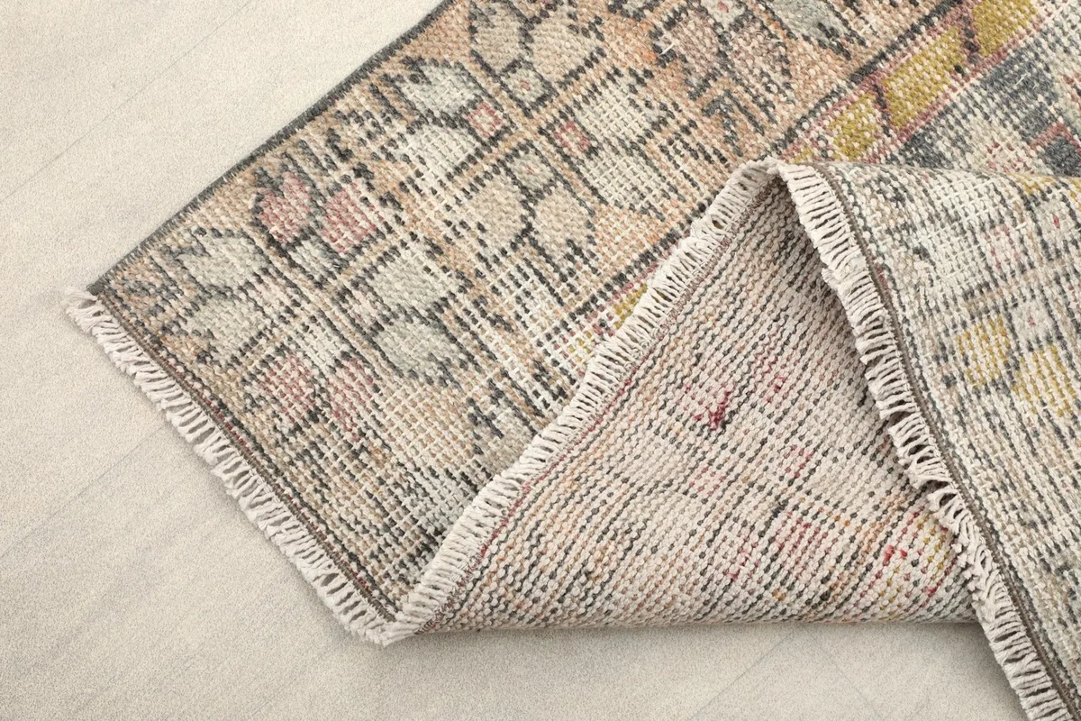 Corner of the rug folded to reveal the hand-knotted wool pile and cotton foundation from the back.