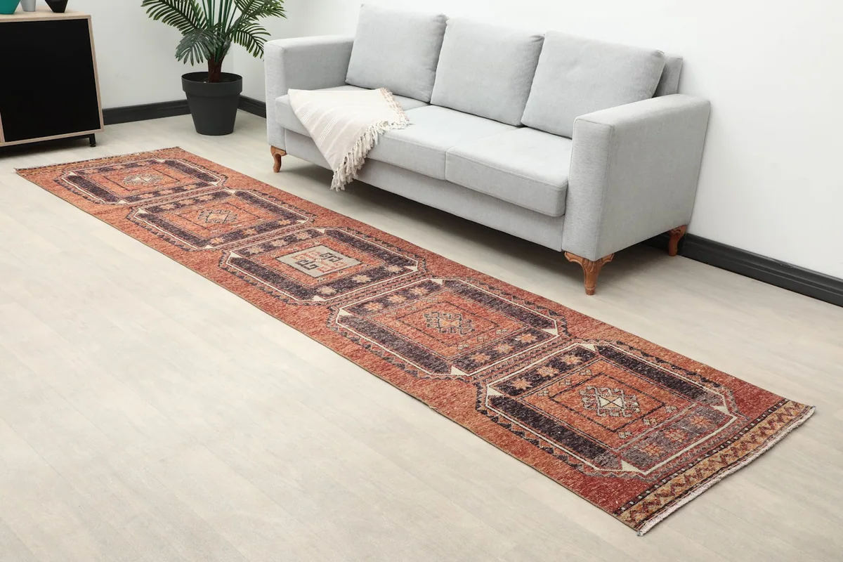 Angle view of the rust runner rug in a room, showing its length.
