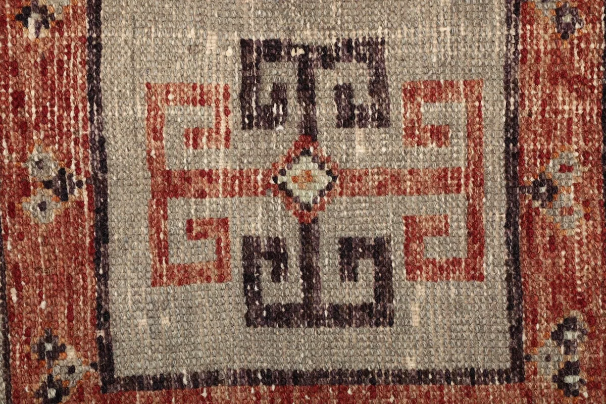 Extreme close-up of the central geometric motif and wool pile texture.