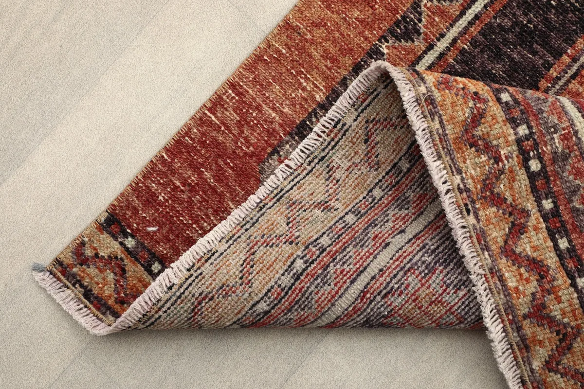 Folded corner of the rug showing the reverse side and cotton foundation.